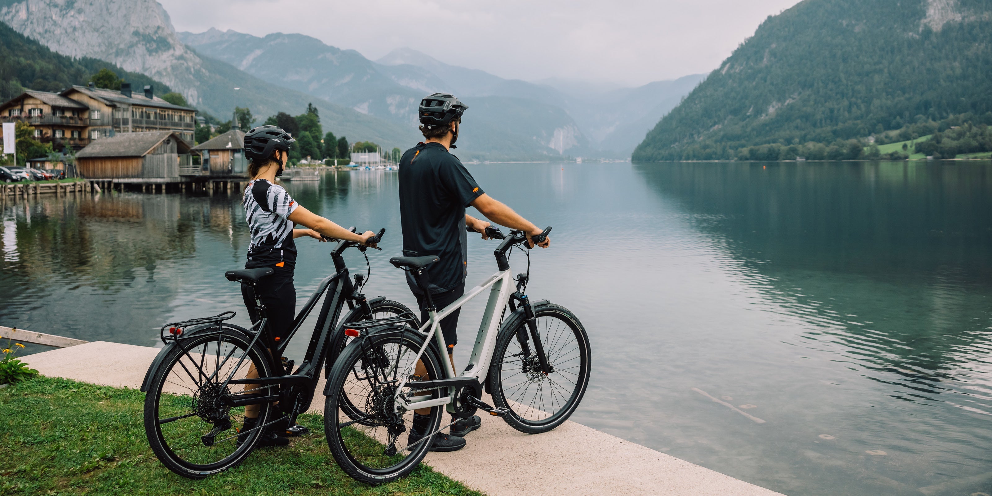 zwei Personen stehen mit ihren E-Bikes von KTM an einem See